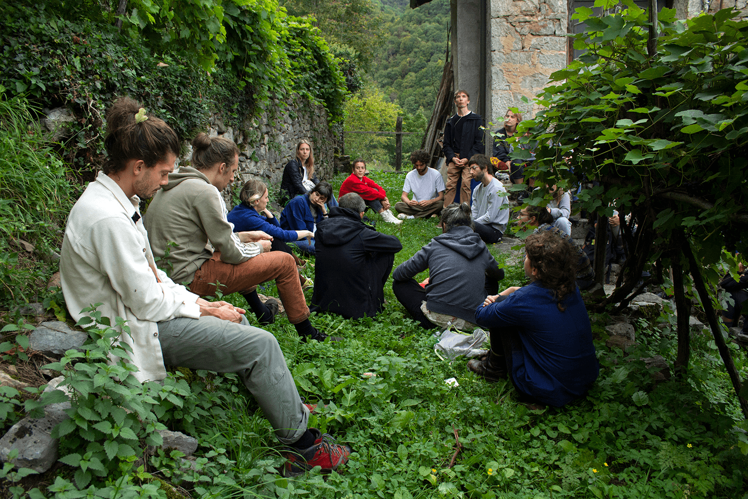 A group of people sitting in a circle in lush green mountain environment